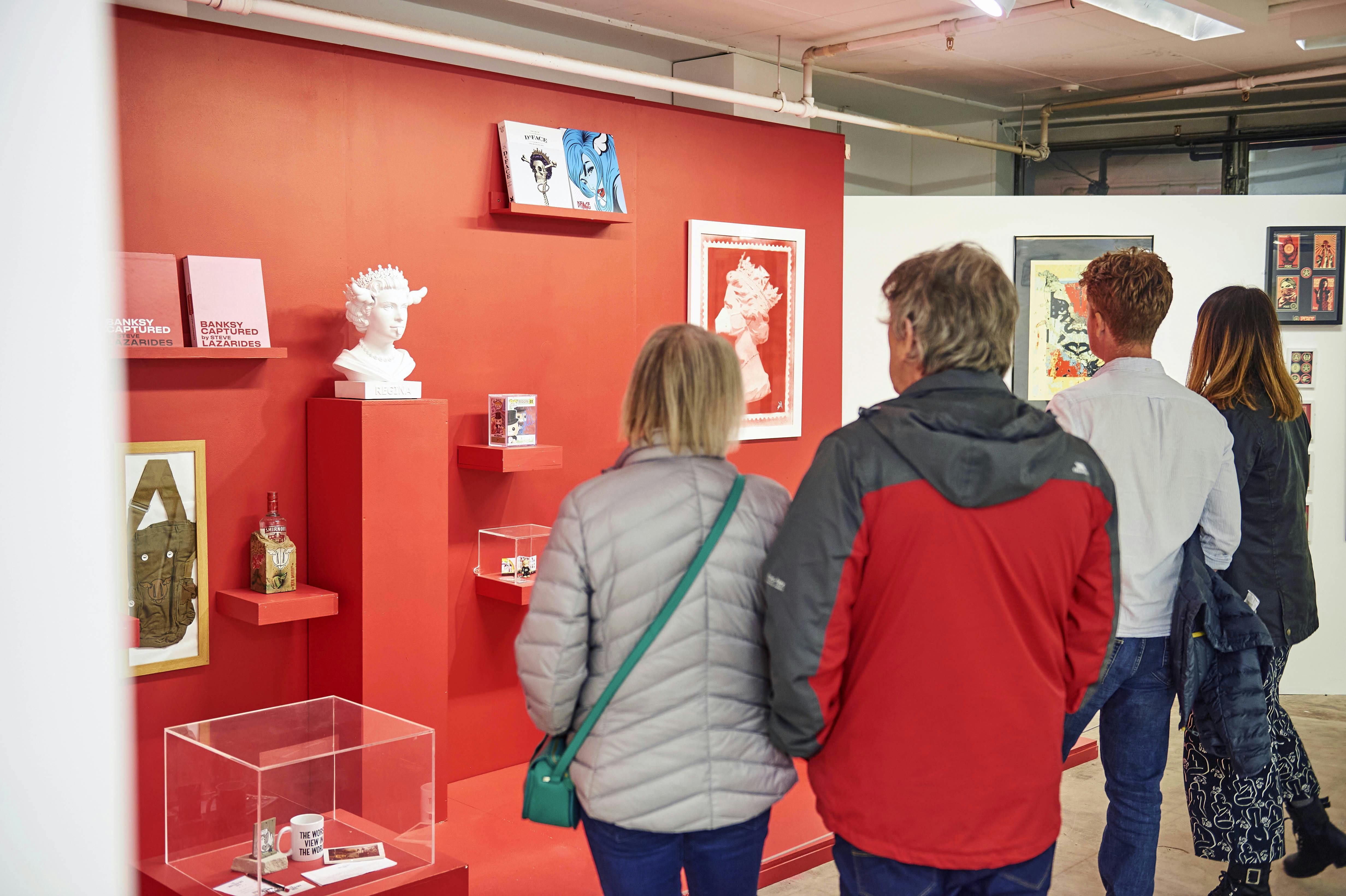 Four people looking at Banksy art works at a gallery exhibition.