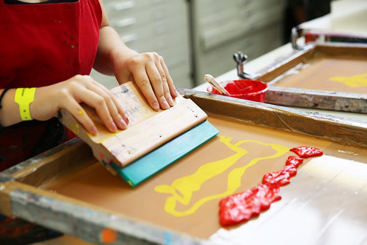 Students screen printing using red paint