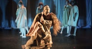 Two acting students on stage holding each other wearing costumes designed by Costume and Performance Design students