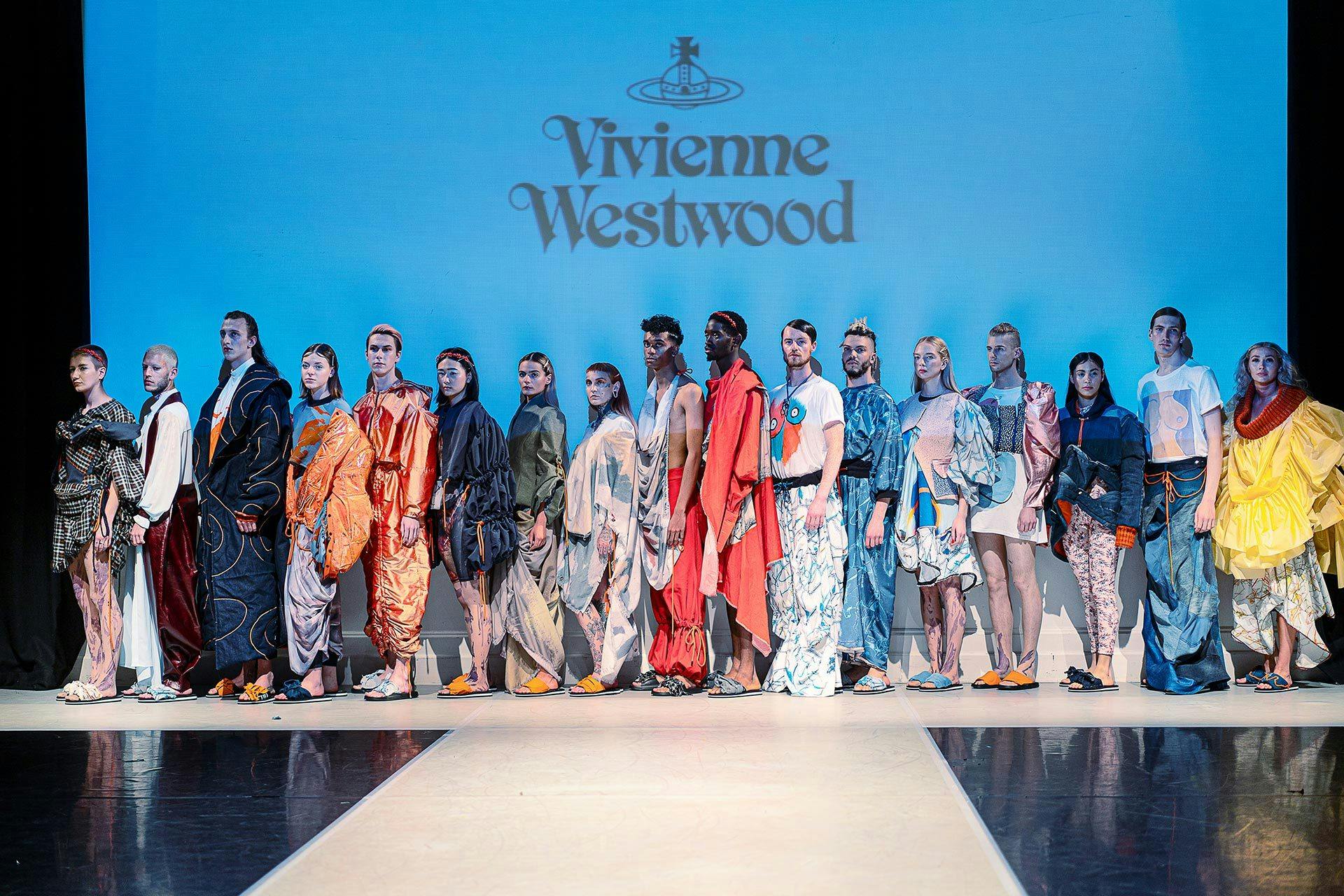 Catwalk full of models in front of a screen that reads 'Vivienne Westwood'.