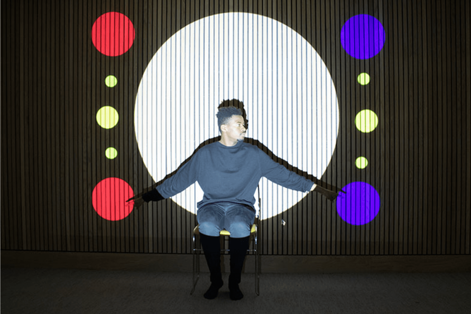 Man sitting on a chair with black and colour circle background