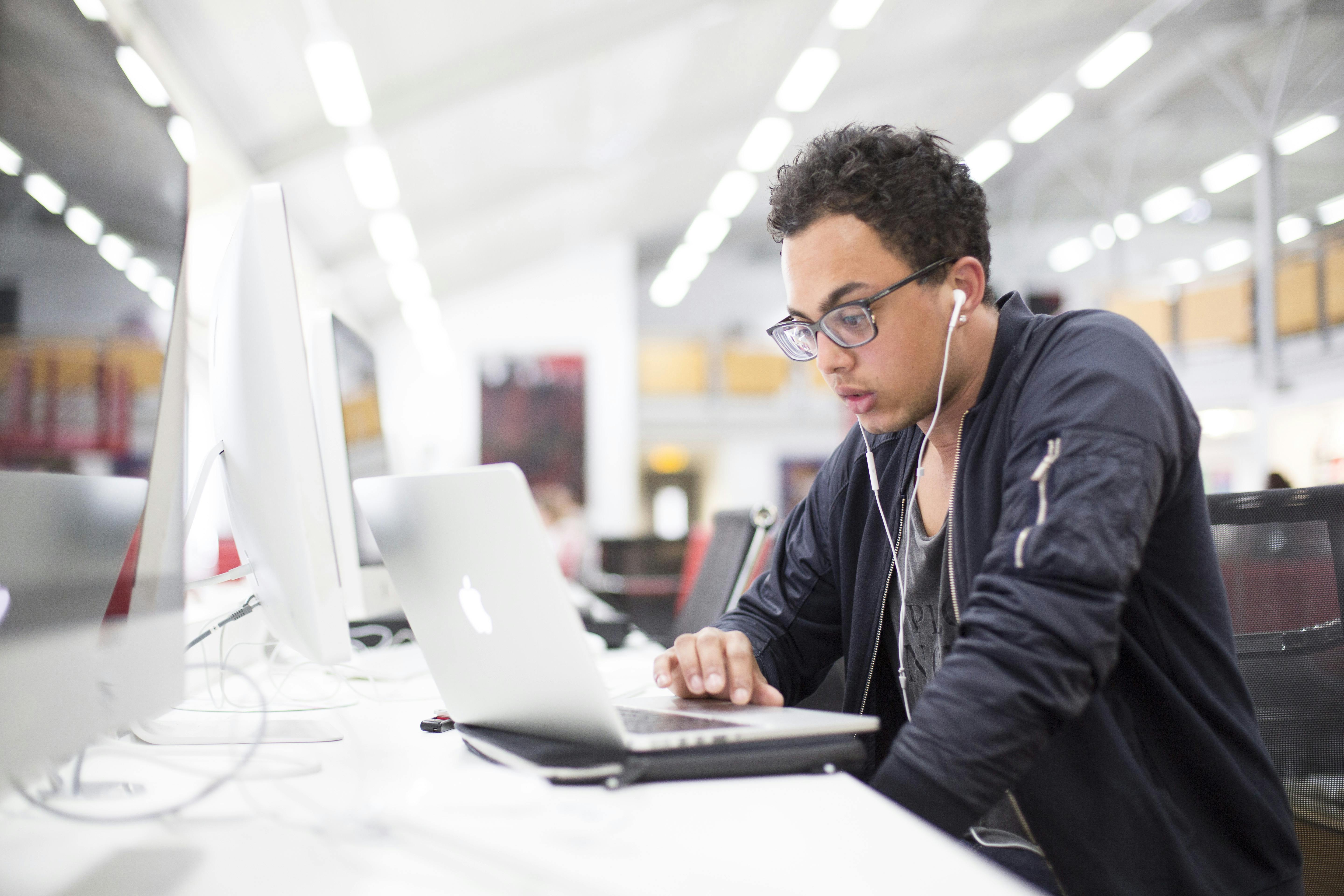 International student using a MacBook in the library