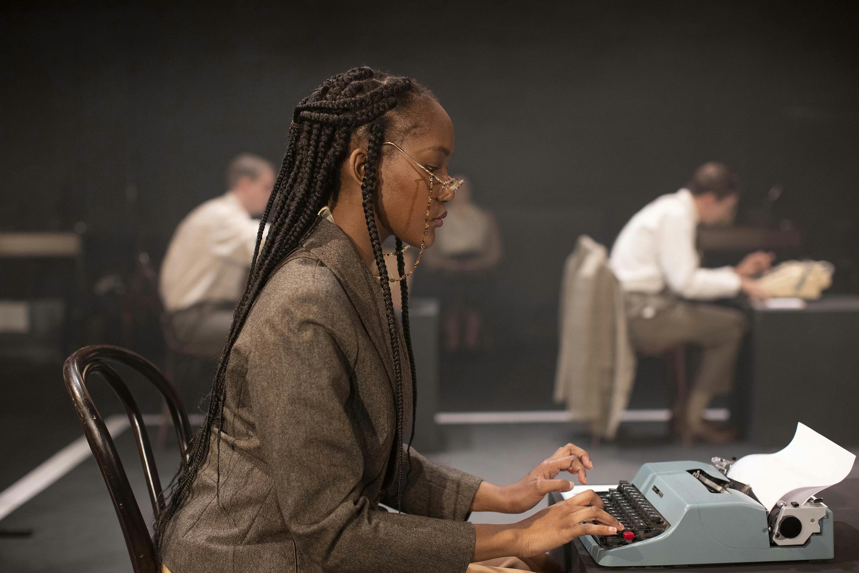 An actress sitting at a typewriter.