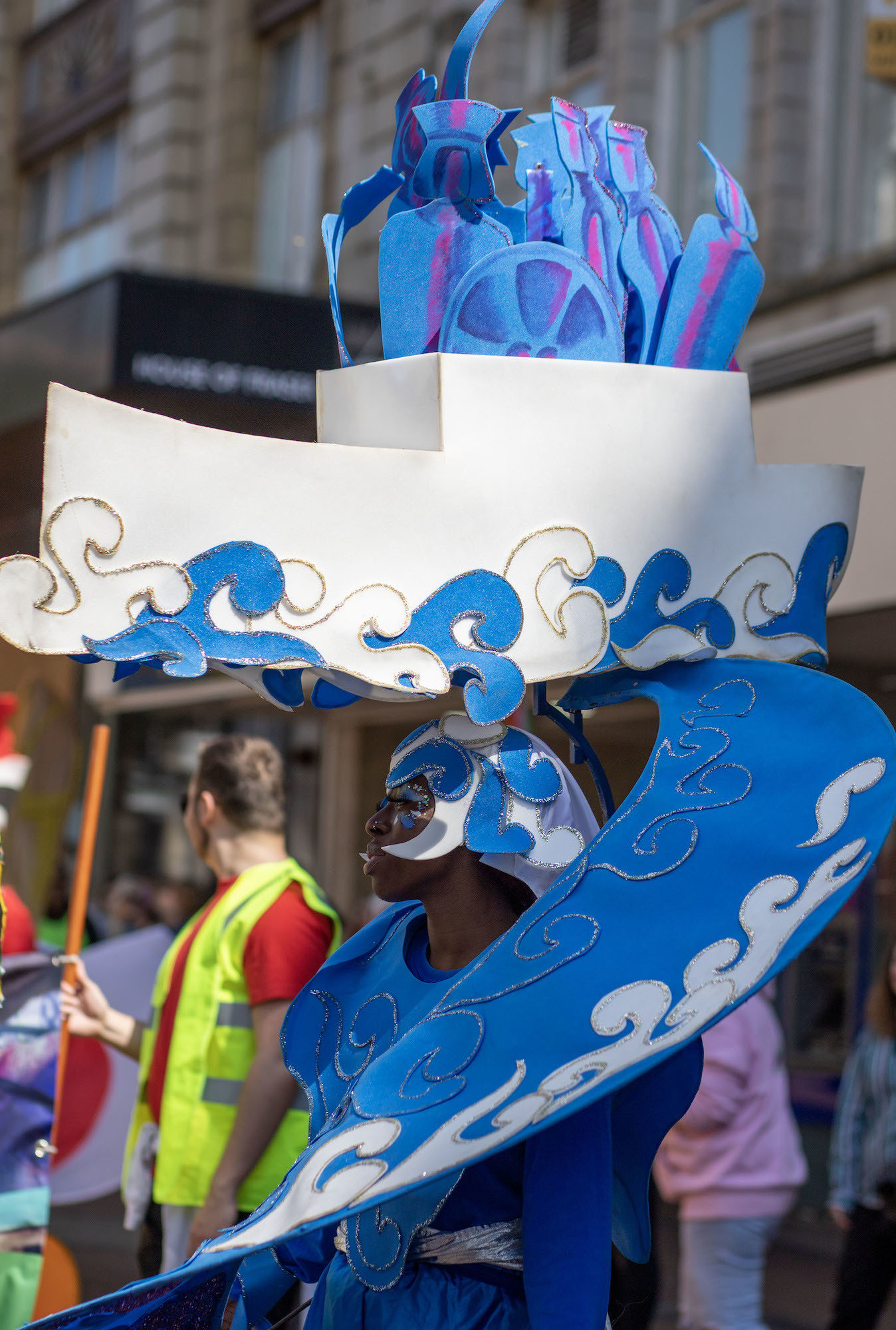 A person in a costume themed around waves and a headdress shaped like a boat with waves lapping the sides.