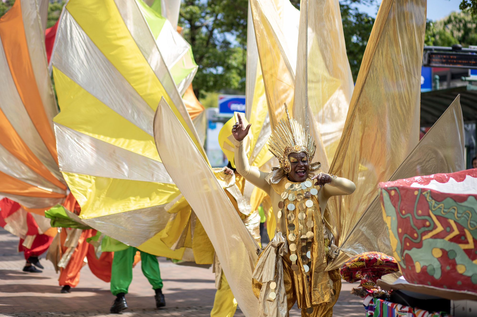 A person in a massive gold-coloured costume at the front of a parade.
