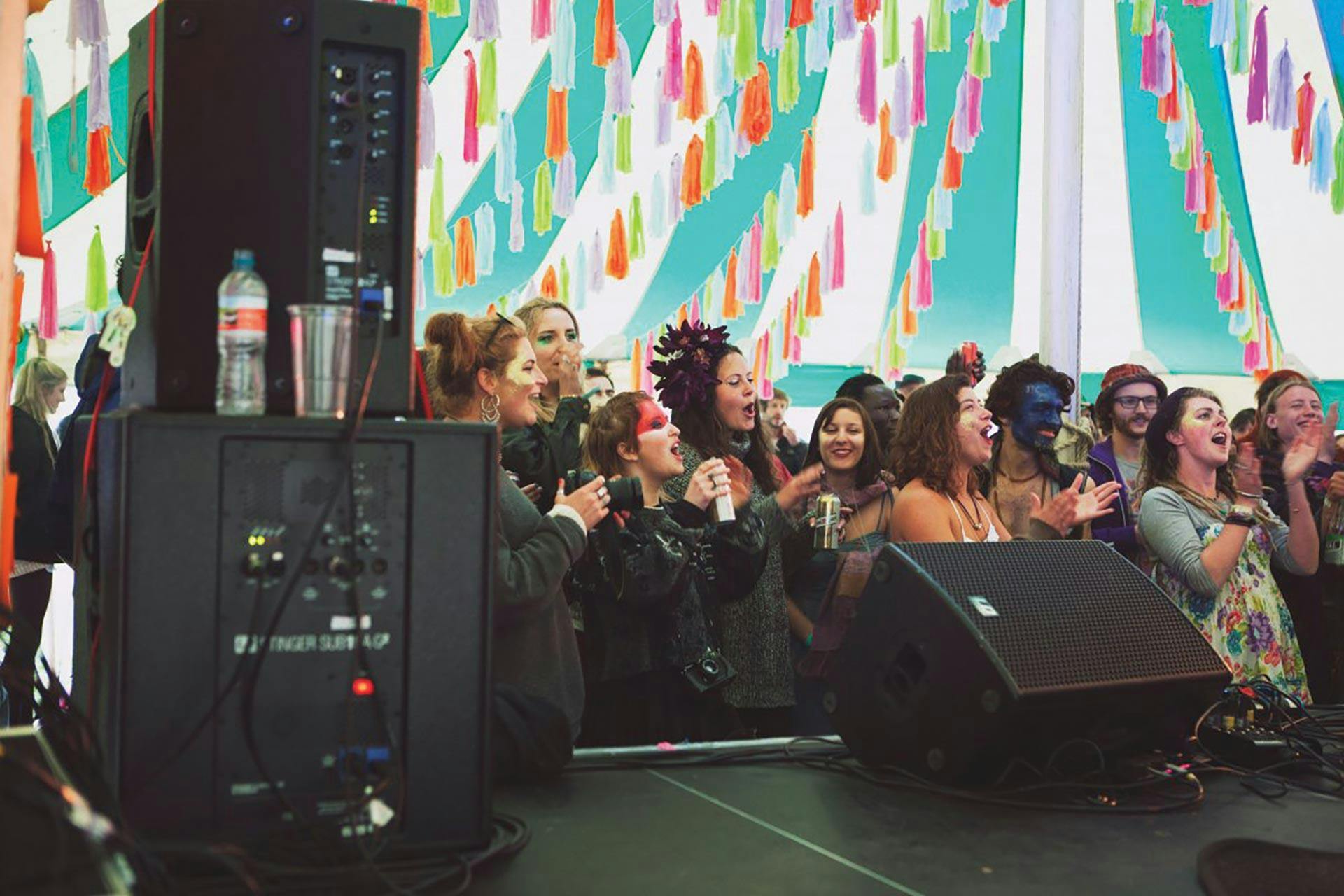 A crowd of students attending a musical event. Speakers and amplifiers appear in the foreground.