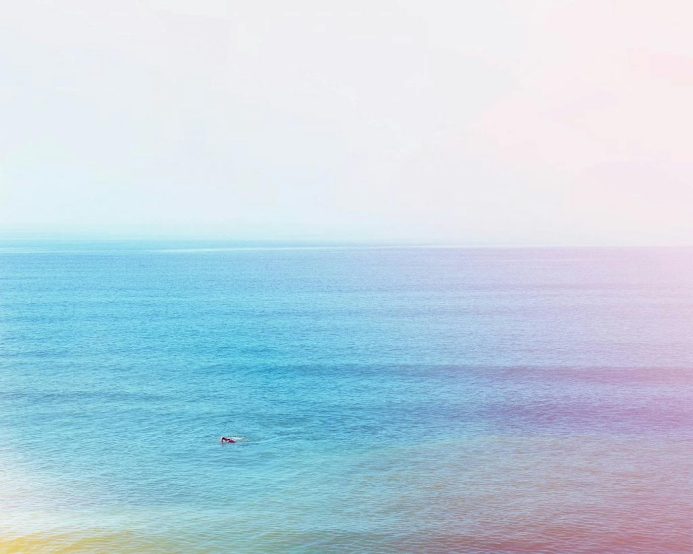 Photograph of a person swimming in the ocean with light burns