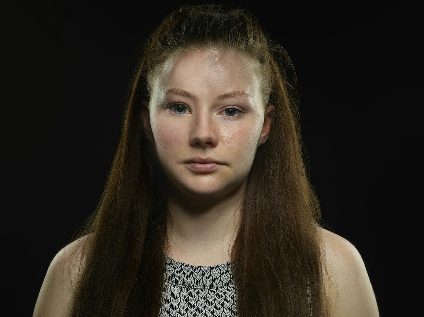 A women with long dark hair in front of a black backdrop