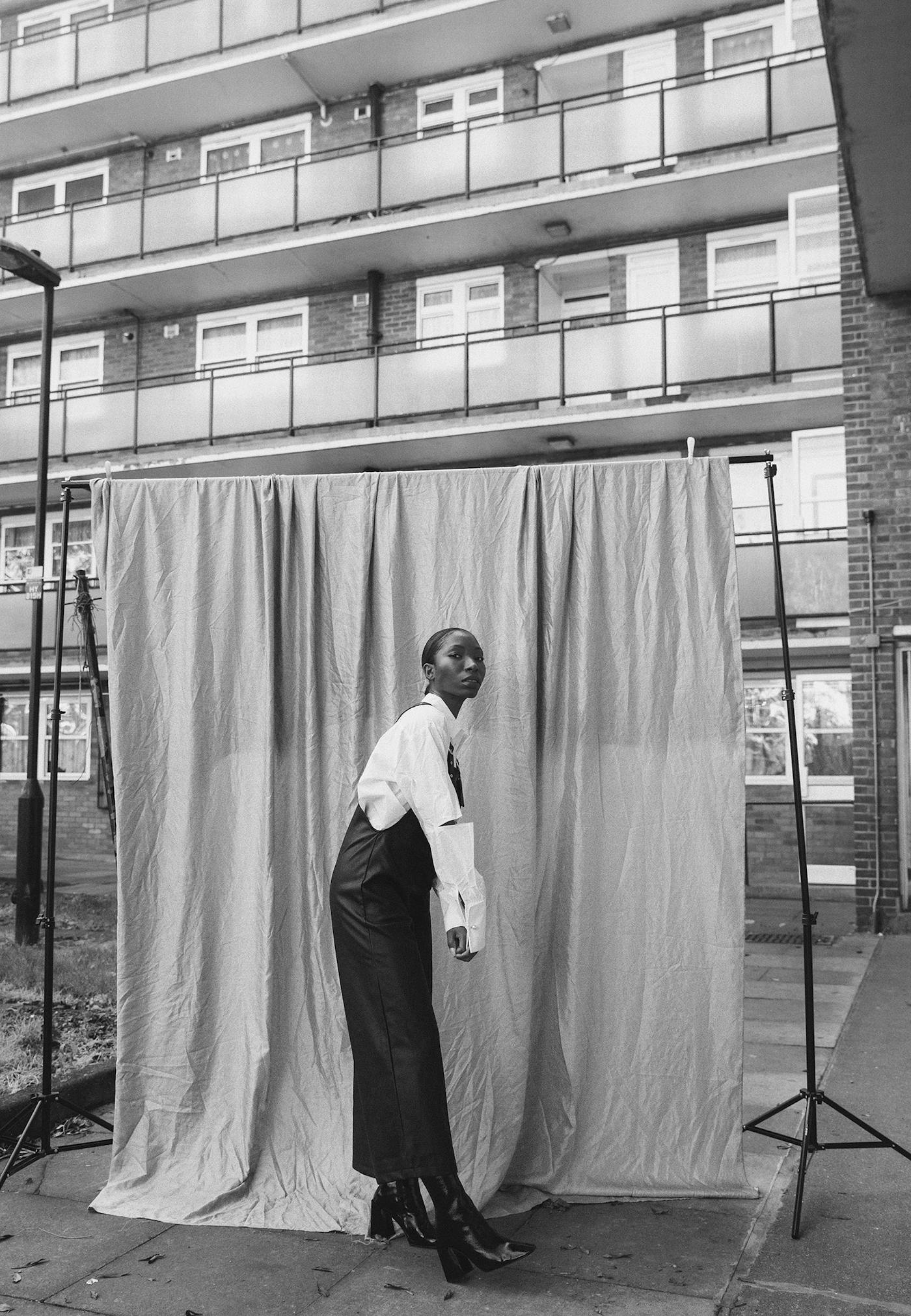 Black and white image of a women standing in front of a plain backdrop in an urban setting