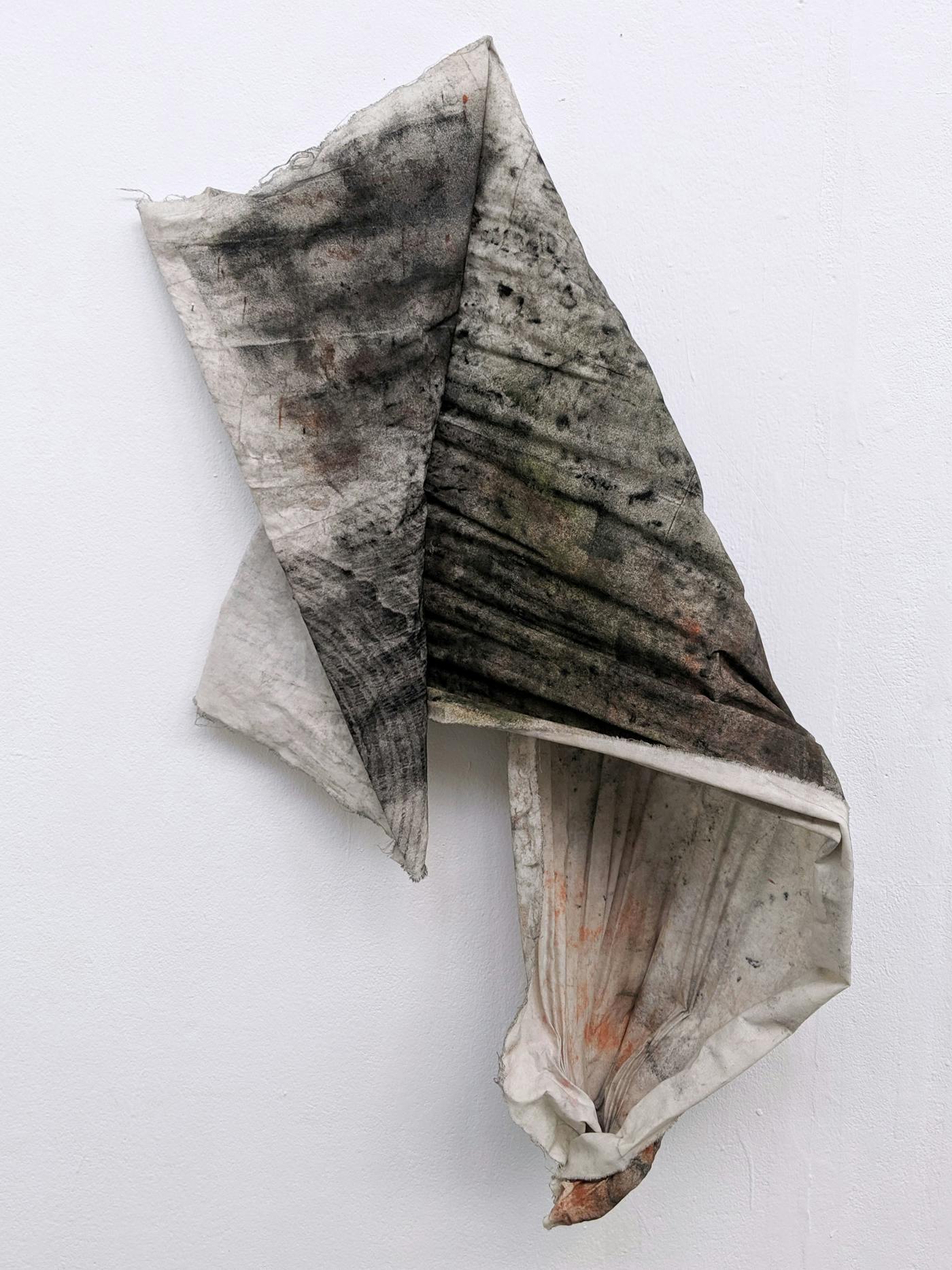 Dark piece of material hanging on a white wall