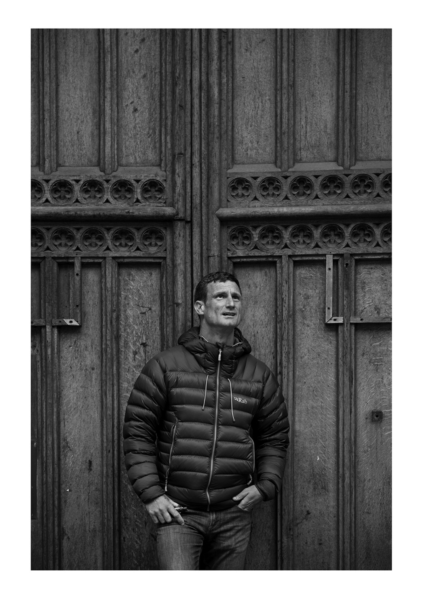 Black and white photograph of a man stood in front of a large door