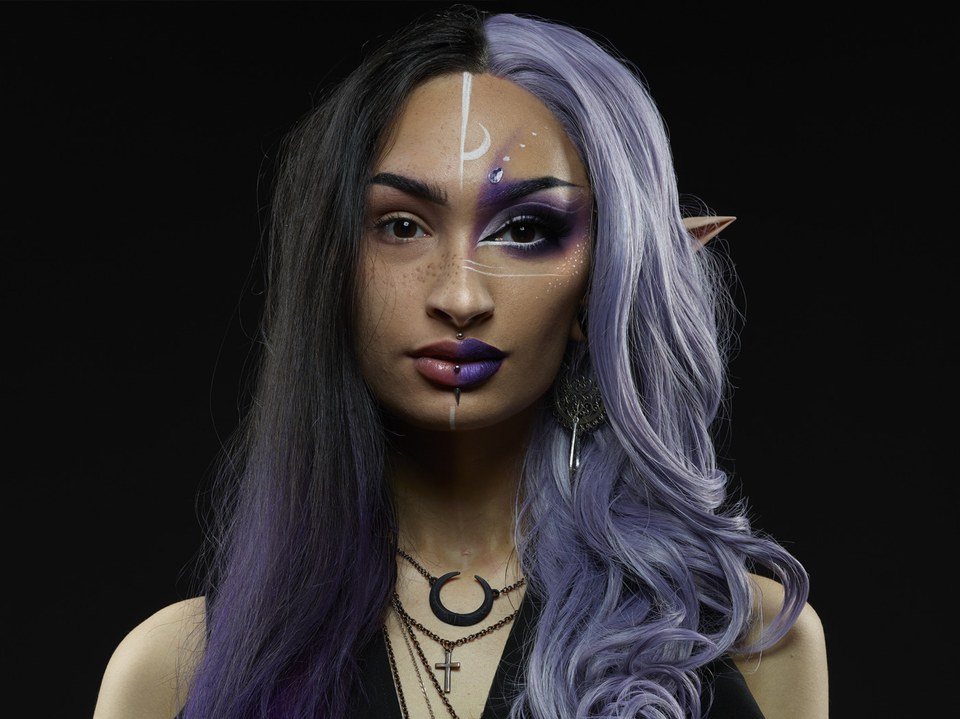 Half a women's face painted to look like a magical alien with purple hair