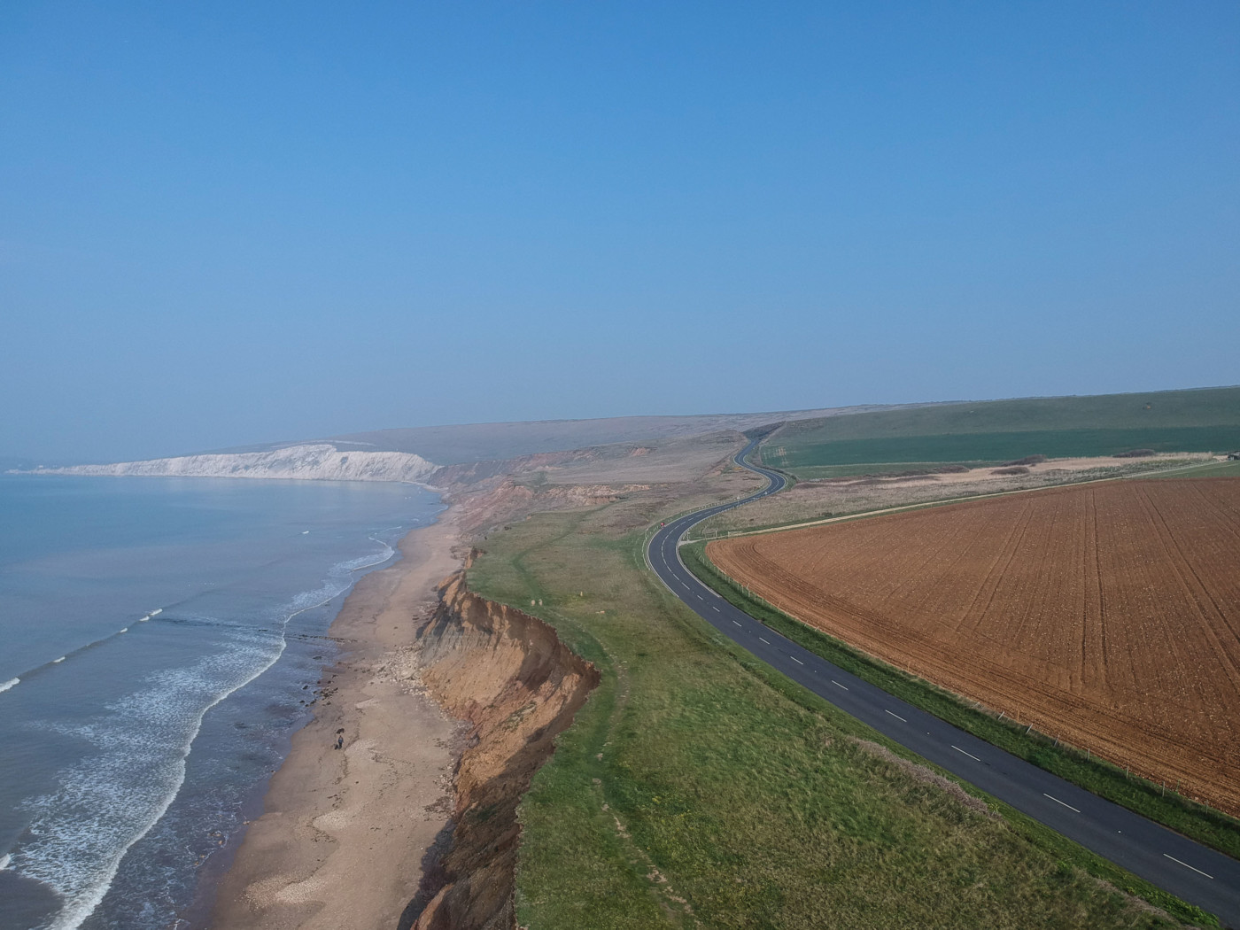 Aerial view of a coast line on a clear day featuring a road on the cliff top