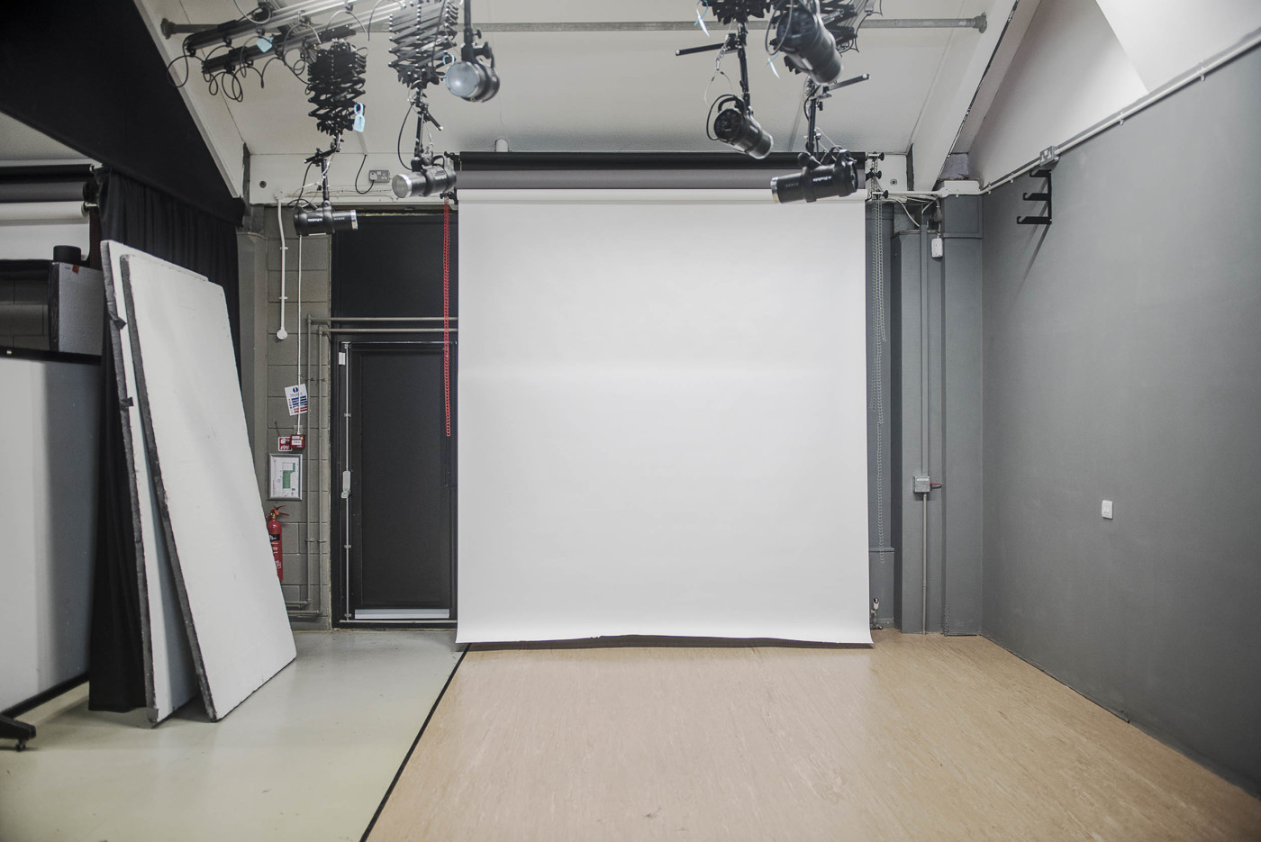 a photography studio with a white backdrop screen and fitted lights in the ceiling