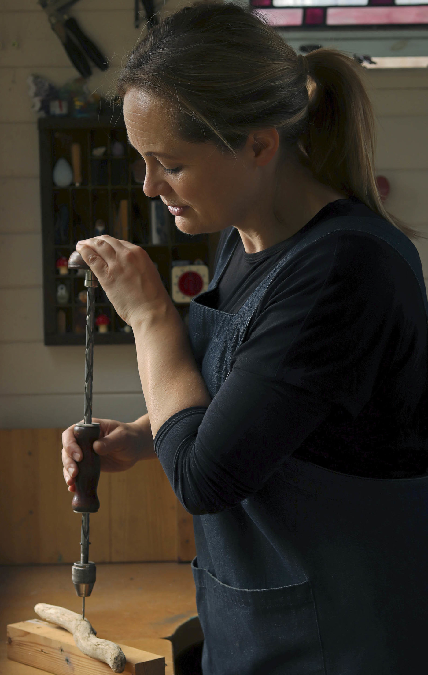 Image of a women using a manual drill on a small piece of wood