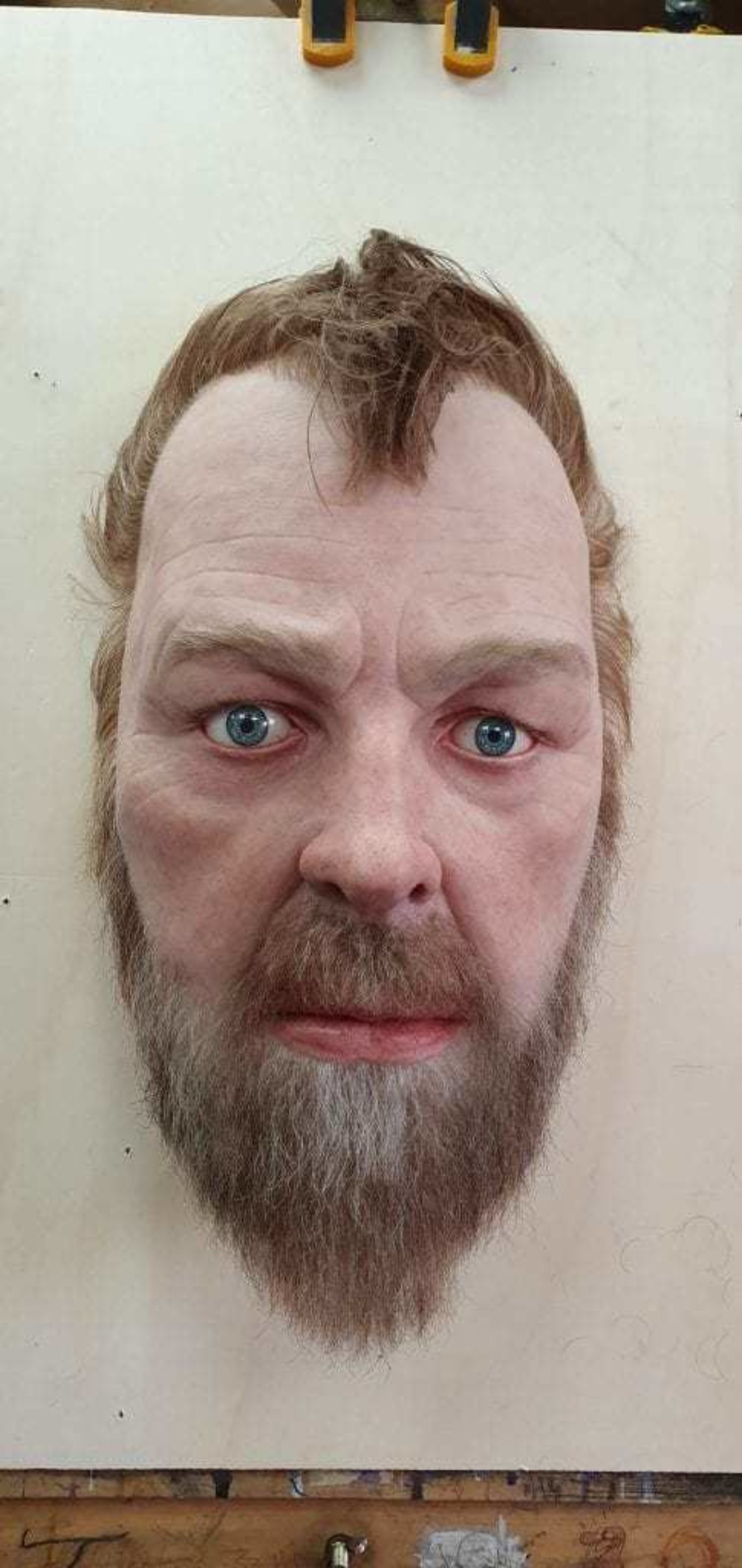 Sculpture of a mans head with a beard and short brown hair.