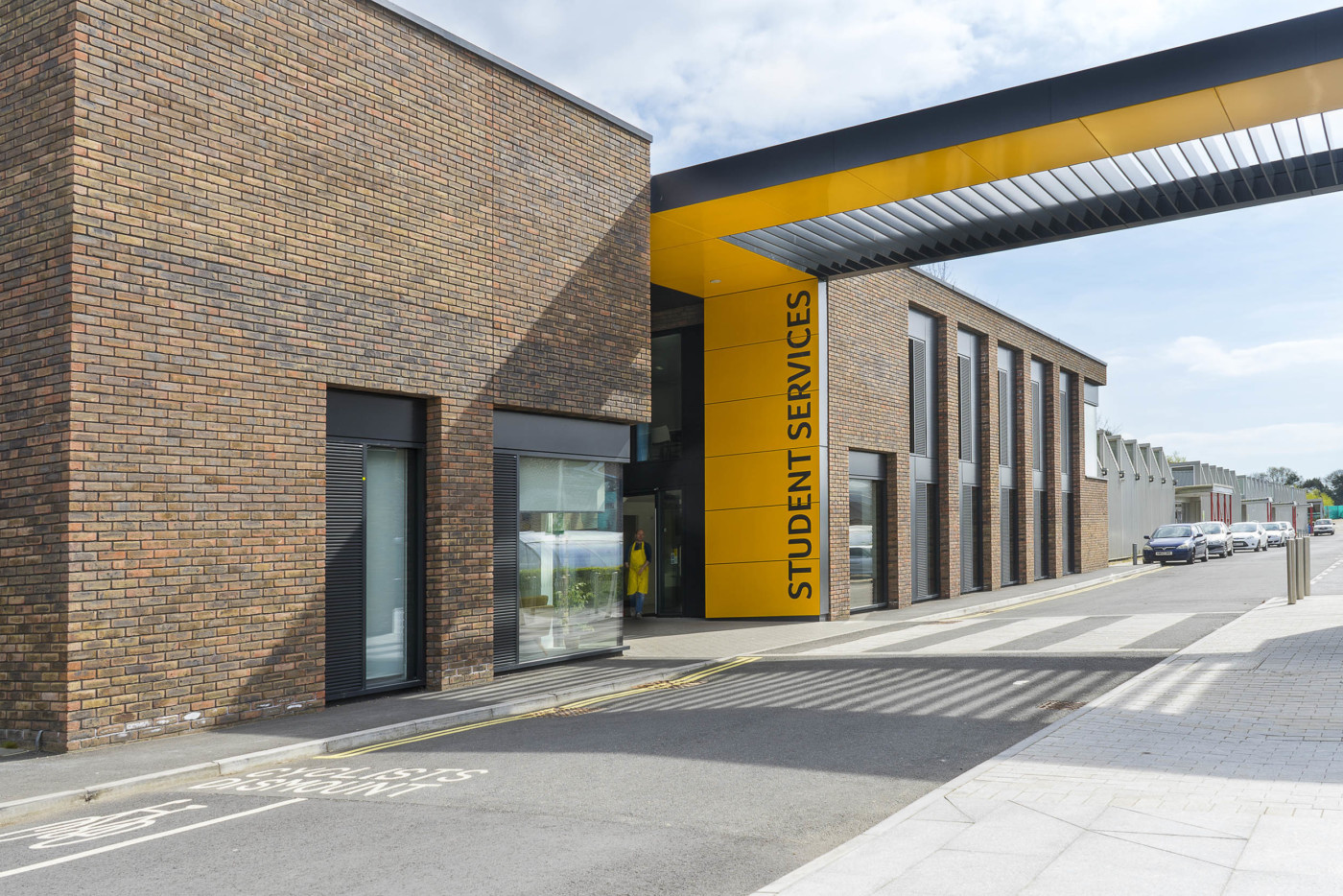 Brown bricked building with a yellow front that reads: Student Services
